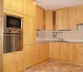 Modern kitchen with light wooden cabinets, stainless steel appliances, and tiled backsplash.