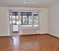Empty room with wooden flooring, white walls, large windows, and a radiator. No furniture or equipment present.