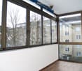 Empty room with large windows, wooden flooring, and white walls. No furniture or equipment present.