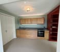 Modern kitchen with wooden cabinets, stainless steel sink, oven, and built-in shelving unit.
