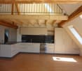 Modern kitchen with white cabinets, black countertop, stainless steel oven, and wooden flooring.