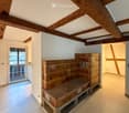 Hallway with exposed wooden beams, tiled floor, and a built-in bench with storage compartments.