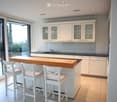 island kitchen, modern white cabinets, black countertops, large windows, sliding glass doors, balcony