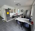 modern kitchen with wooden cabinets, granite countertop, stainless steel appliances, and a dining area with a marble table