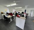 Modern office with desks, chairs, monitors, cabinets, and a window.
