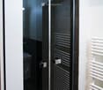 Modern bathroom with a glass-enclosed shower, black tiles, and a white radiator.