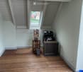 Wooden deck with a skylight window, grill, wooden shelf, flower pot, and storage box.