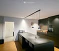 Modern kitchen with dark grey cabinets, a central island, and pendant lighting. Includes a microwave, oven, sink, and various small items on the counter.