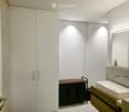 Modern bathroom with white walls, a sink on a wooden vanity, a large mirror, and a white cabinet with silver handles.