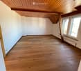 empty room with wooden floor, white walls, wooden ceiling, two windows with balcony, power outlet and switch on the wall