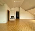 Spacious living room with vaulted wooden ceiling, hardwood parquet flooring, and a fireplace. The room has a bright and airy feel with ample natural light coming in.