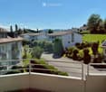 Balcony overlooking a residential neighborhood with houses, trees, and a clear blue sky.
