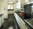 modern kitchen with black tiles, white cabinets, black countertops, stainless steel appliances, large windows