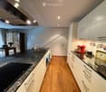 Modern kitchen with granite countertops, white cabinets, stainless steel appliances, and a wooden dining area visible in the background.