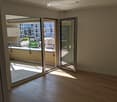 Empty room with wooden flooring and large glass sliding doors leading to a balcony area.