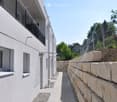 Modern corridor with tiled flooring, stone retaining wall, and metal railing on the left side.