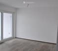 Empty room with wooden flooring, white walls, and a large sliding glass door leading to an outdoor area.