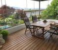 Wooden deck with a table, chairs, and potted plants, offering a scenic mountain view.