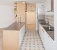 Modern kitchen with wooden counter, stainless steel sink, and patterned tile floor.