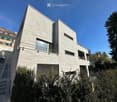 Modern, multi-story building with a raised ground floor, large windows, and a sleek, contemporary design.
