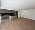 Modern kitchen with grey cabinets, a central island, and wooden flooring.