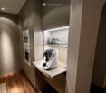 Modern kitchen with wooden flooring, built-in oven, countertop with a blender, and open shelving holding bowls and glasses.