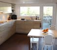 modern kitchen, wooden countertops, oak cabinets, white chairs, dining table, open balcony with view, double sink, gas stove, built-in appliances