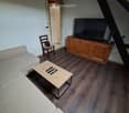 Living room with a sofa, coffee table, chair, television on a wooden cabinet, and remote controls on the coffee table.