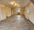 large room, wooden flooring, white walls, multiple doors, windows, radiators, central lighting