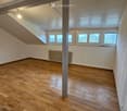 Empty room, hardwood flooring, white ceiling, white walls, 3 windows, radiators, view from windows