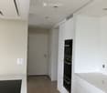Modern kitchen with white cabinets, an induction stove, and a built-in oven. The space features recessed lighting and a neutral color palette.