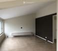 Empty room with beige tiled floor, white walls, and a built-in cabinet under a window. No furniture or equipment present.