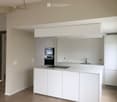 Modern kitchen with white cabinets, a central island, built-in oven, and sink.