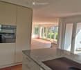Modern kitchen with granite countertop, induction cooktop, built-in oven, and light-colored cabinets.