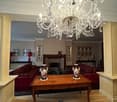 Elegant living room with a large chandelier, red sofas, wooden coffee table, fireplace, and decorative vases.