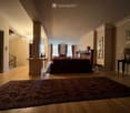 Elegant living room with wooden flooring, a large patterned rug, a red sofa, a chandelier, and several decorative items including vases and picture frames.