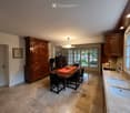 large wooden cabinet, dining table with 6 chairs, chandelier, kitchen with double sink, open doors