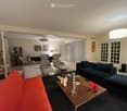 modern living room, two sofas, coffee table, hardwood flooring, two doors, ceiling lamp, paintings