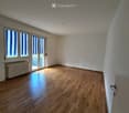 Empty room with wooden flooring, white walls, large windows with blinds, and a radiator under one window.
