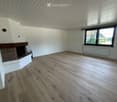 Empty room with wooden flooring, white walls, a fireplace, and a large window with blinds.