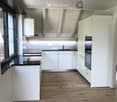 Modern kitchen with white cabinets, wooden flooring, and stainless steel appliances including a sink and oven.