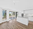 Modern kitchen with white cabinets, a central island, and large sliding glass doors leading to a balcony.