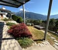 Garden area with a stone pathway, small wooden deck, and a view of mountains in the background.