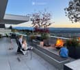 Modern rooftop terrace with a fire pit, seating area, and scenic mountain view.