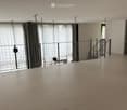 Empty room with wooden floor, large windows with curtains, metal railing, and a staircase leading to another level.