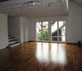 Empty room with wooden flooring, large windows, and a staircase leading upwards.