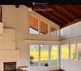Bright living room with a fireplace, large windows, and a bench, featuring a hexagonal tile floor and wooden ceiling.
