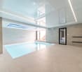 Modern indoor swimming pool area with large skylights, tiled walls, and a sleek design.