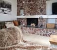 Living room with a stone fireplace, a large fur throw on a sofa, and a picture frame on the wall.