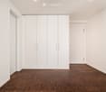 Empty room with white walls, wooden flooring, and built-in white wardrobes. No furniture or personal items present.